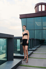 Fashion shoot with a professional model, a girl on the roof of a building in stylish clothes.