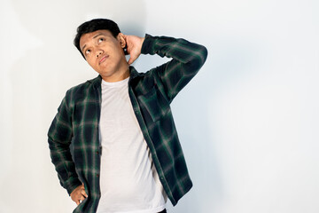 Asian man in green shirt scratching the back of his head with a confused or elemental expression, standing against a white studio background