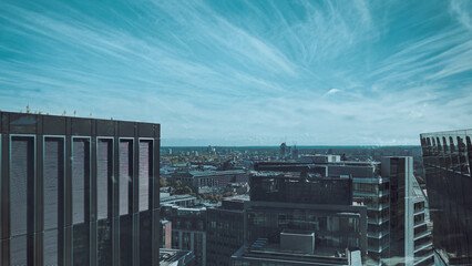 Urban skyline panorama with tall glass buildings under blue sky.