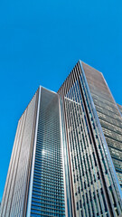 Fototapeta premium Urban skyline panorama with tall glass buildings under blue sky.