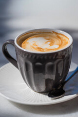 textured gray ceramic mug filled with frothy coffee, adorned with delicate latte art