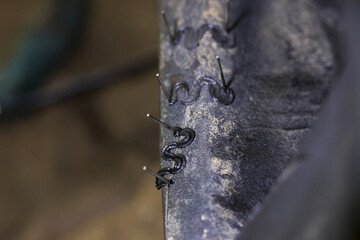 Precise close up of plastic welder repair work on dark bumper. Detailed macro view shows hot staple melting and joining crack for strong, industrial fix and restoration