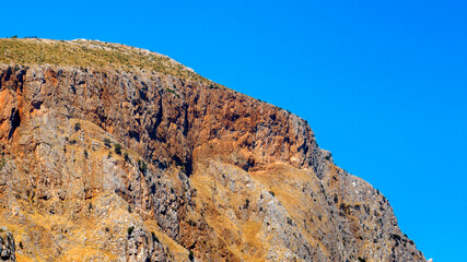 Slope of a rocky mountain. Blue sky in the background.