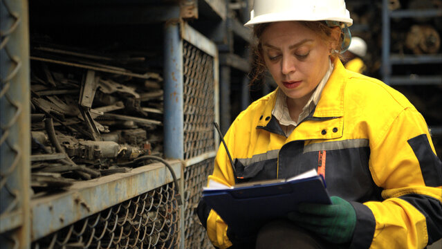 Female engineers wearing safety helmet gear inspecting car parts inventory