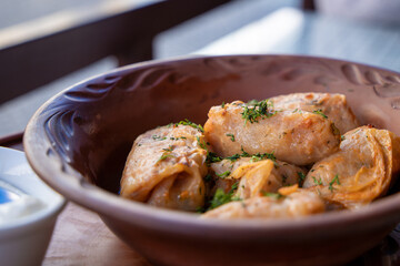 Stuffed cabbage leaves, cabbage rolls, and dolma in a clay pot, served with sour cream. Cabbage wraps. Chow Farsi, dolma, sarma, cabbage rolls, or golabki. Flat lay, arrangement, overhead.