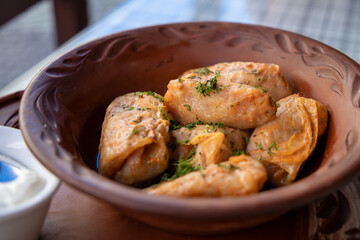 Stuffed cabbage leaves, cabbage rolls, and dolma in a clay pot, served with sour cream. Cabbage wraps. Chow Farsi, dolma, sarma, cabbage rolls, or golabki. Flat lay, arrangement, overhead.