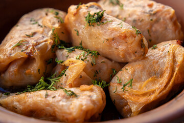 Stuffed cabbage leaves, cabbage rolls, and dolma in a clay pot, served with sour cream. Cabbage wraps. Chow Farsi, dolma, sarma, cabbage rolls, or golabki. Flat lay, arrangement, overhead.