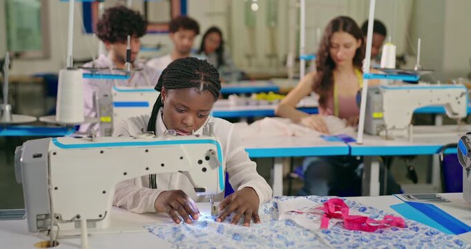 African young adult gen z lady female wear tape around neck indoor class room learn good sewing machine happy teen girl pupil do casual self craft skill new college day place