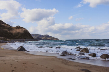 Tranquil Rocky Shoreline Under Blue Sky and Clouds