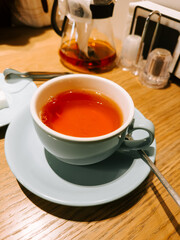 Warm tea served in a light blue cup on a wooden table during a cozy cafe visit