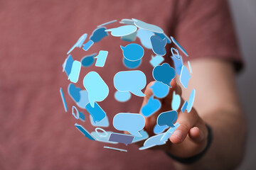 A 3D sphere made of speech bubbles held in hand symbolizing communication, global network,...