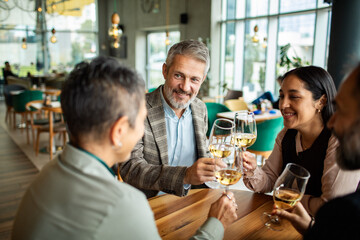 Mature adults toasting wine at a cafe