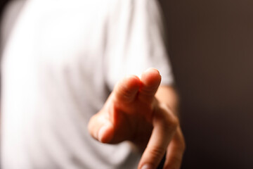 Naklejka premium Focus on the index finger, a person is pointing at something, touching a surface or screen, on a blurry background.