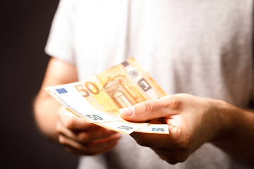 A person holding Euro banknotes, ideal for financial topics like finance, money, economy, wealth,...