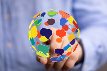 Hand reaching for speech bubbles sphere, depicting international dialogue and social interaction....