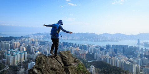 Successful woman hiker stand on the cliff edge oustretched arms to the beautiful hong kong