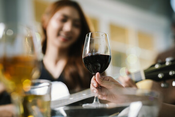 A woman smiling and toasting with a glass of wine during an evening celebration, surrounded by soft bokeh lights and a warm atmosphere.
