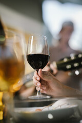 A woman smiling and toasting with a glass of wine during an evening celebration, surrounded by soft bokeh lights and a warm atmosphere.