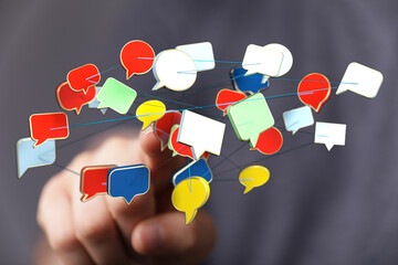 A hand reaching towards colorful speech bubbles connected by lines, symbolizing communication,...