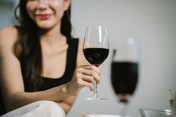 A woman smiling and toasting with a glass of wine during an evening celebration, surrounded by soft bokeh lights and a warm atmosphere.
