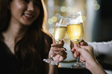 A woman smiling and toasting with a glass of wine during an evening celebration, surrounded by soft bokeh lights and a warm atmosphere.