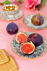 Tea with figs and cookies on pink background