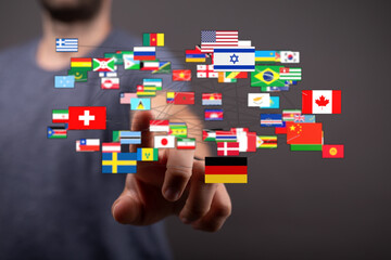 Concept of international connections and global cooperation. A person's hand is interacting with a network of flags of various countries. Highli