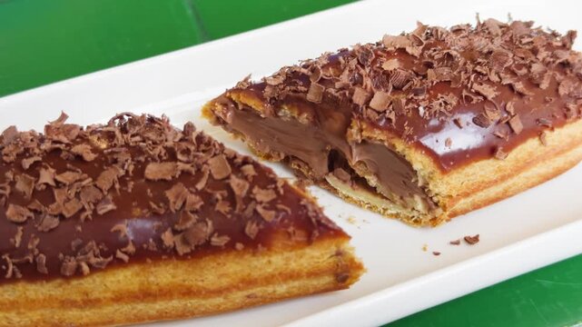 Fresh sweet eclair cake with cream cheese and chocolate chips on the table in a cozy cafe. High quality 4k footage