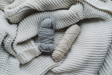 Knitting tools and various yarn balls are arranged on a soft, textured blanket, creating a warm, inviting atmosphere for crafting.