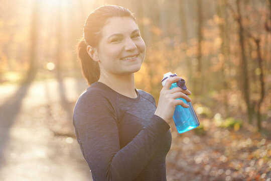 Portrait of a sporty young woman with water bottle on a sunny autumn morning outdoors	