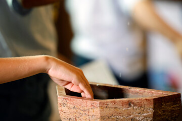 Saint Nicolas church. Hand taking holy water from a marble font. Meursault. France.