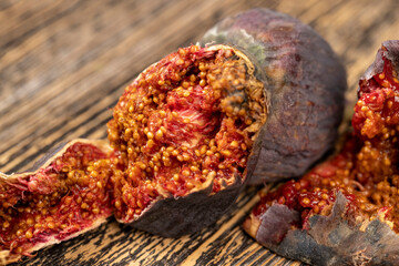 moldy whole overripe and spoiled figs with seeds on a table, moldy spoiled figs with lots of grains and red spoiled flesh on a wooden table