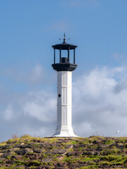 Lighthouse with blue sky and stone foreground. Lighthouse is situated in Maryport, Cumbria.