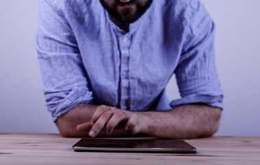 A man interacts with a tablet device on a wooden surface. Demonstrating technology use, creativity and innovation. Simple and natural lighting. © vegefox.com