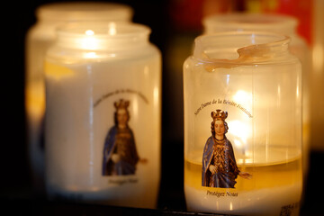Sanctuary of the Benite Fontaine. Votive candles dedicated to Our Lady of the Benite Fontaine, burning in a dimly lit pilgrimage chapel. La Roche sur Foron.  France.