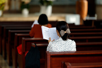 Catholic church. Woman praying the rosary. Hail Mary, full of grace. Ho Chi Minh city. Vietnam.