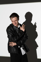 Stylish teenage man enjoying the moment while casting a playful shadow on the wall
