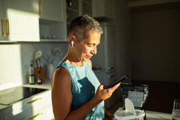 Senior woman using smartphone in kitchen