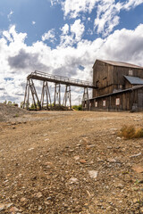 Remains of the historic Olav's mine, mining shaft and generator shed stand in R&oslash;ros, Norway. The area is quiet with debris scattered around and clouds overhead