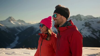 Happy couple hiking in snowy mountains enjoying winter exploration with backpacks under bright sunlight.