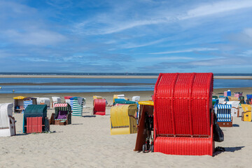 Bunte Strandkoerbe aus Korbgeflecht stehen am Strand mit Meer und Himmel im Hintergrund auf der...