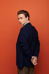 Fototapeta premium Stylish young man poses confidently against vibrant orange background in modern youth culture scene