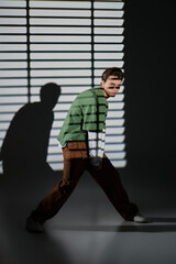 Stylish teenager poses confidently in a modern setting with dramatic shadows