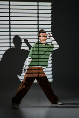 Stylish young man poses creatively in a dramatic light and shadow setting