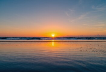 Fototapeta premium Sunrise over calm ocean with golden glow on wet beach