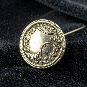 Ornate silver button pin on velvet
