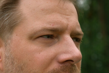 Fototapeta premium Human Man Face extreme close up. Macro Shot of Male Green Eye. Vision. Healthy Eyesight Concept. Front view. Mature Adult Looking at Camera, Blinking Eyelashes. Eye Opening Wide. Soft Selective Focus
