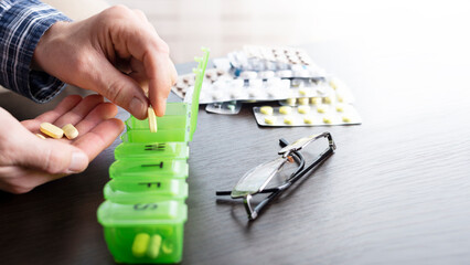 Middle aged caucasian man distributing scheduled dose of medication in dosette box