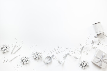 Festive party decoration in silver color with gift box and carnaval caps on white background, top view