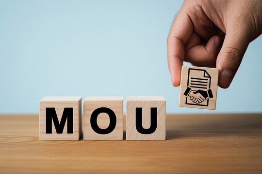 Hand placing a document cube next to mou letter cubes forming a memorandum of understanding agreement